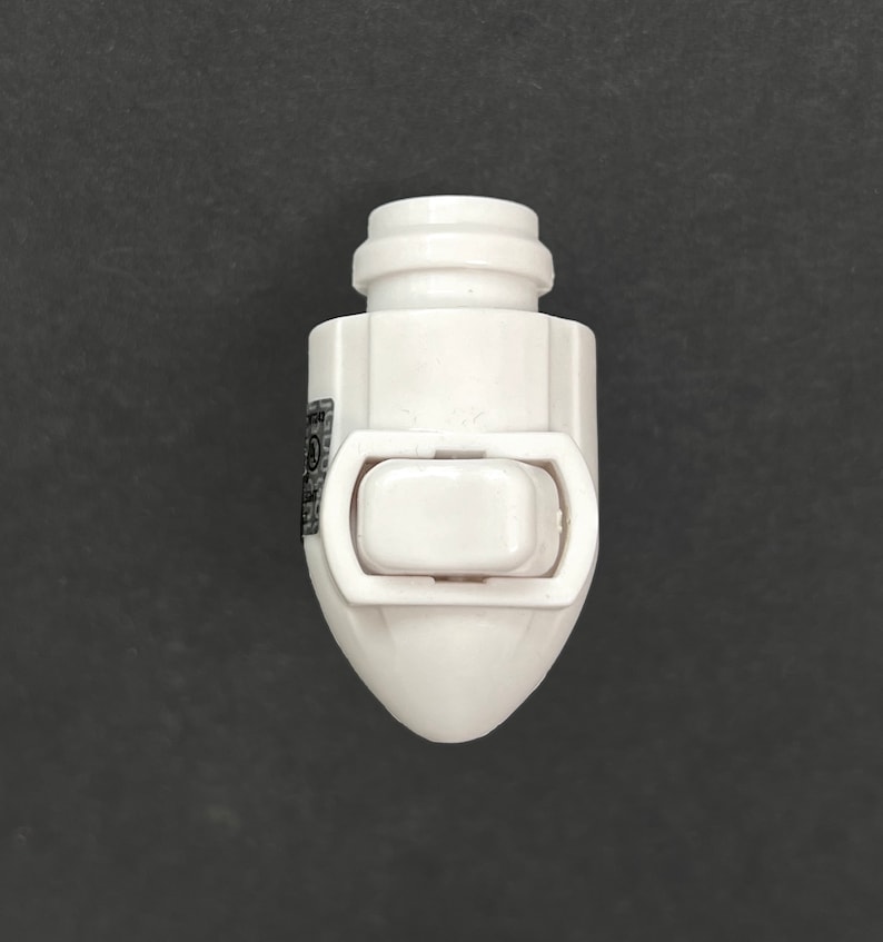Op de afbeelding: Witte plastic lichtschakelaar met een enkele wipschakelaar. De schakelaar heeft een afgerond, kogelvormig ontwerp.