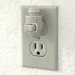 Op de afbeelding: Een wit stopcontact met een witte kunststof veiligheidsafdekking. Het stopcontact heeft een standaardconfiguratie met drie pennen.