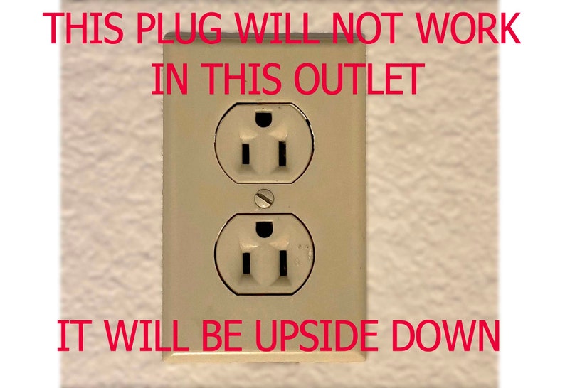 Op de afbeelding: Een close-up van een standaard stopcontact met de tekst "THIS PLUG WILL NOT WORK IN THIS OUTLET IT WILL BE UPSIDE DOWN" erboven.
