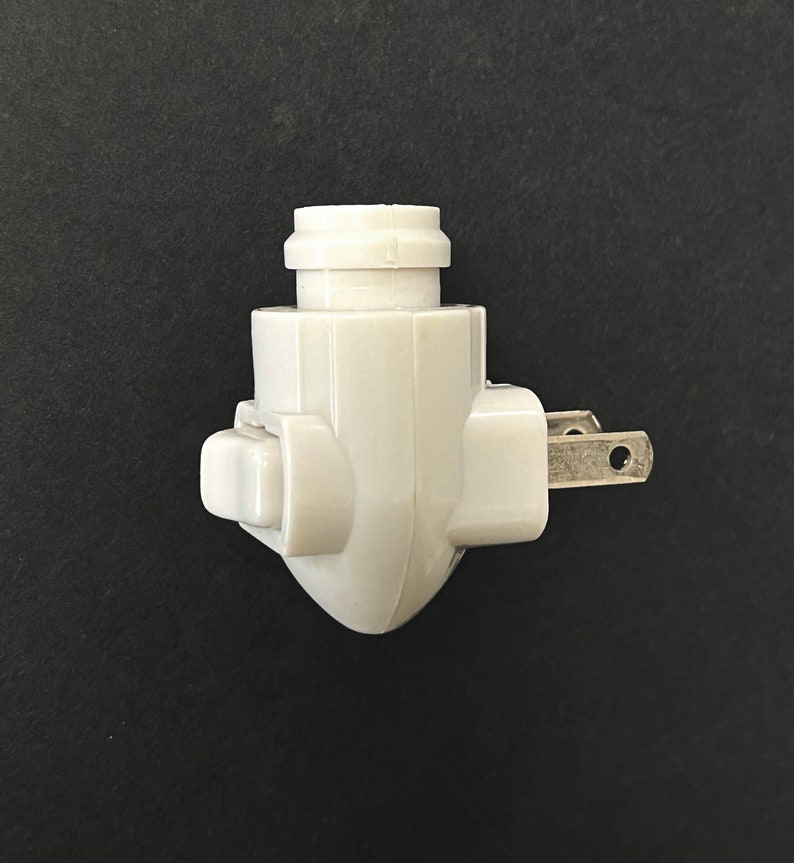 Op de afbeelding: Witte plastic nachtkastje stekker met een schakelaar aan de zijkant.