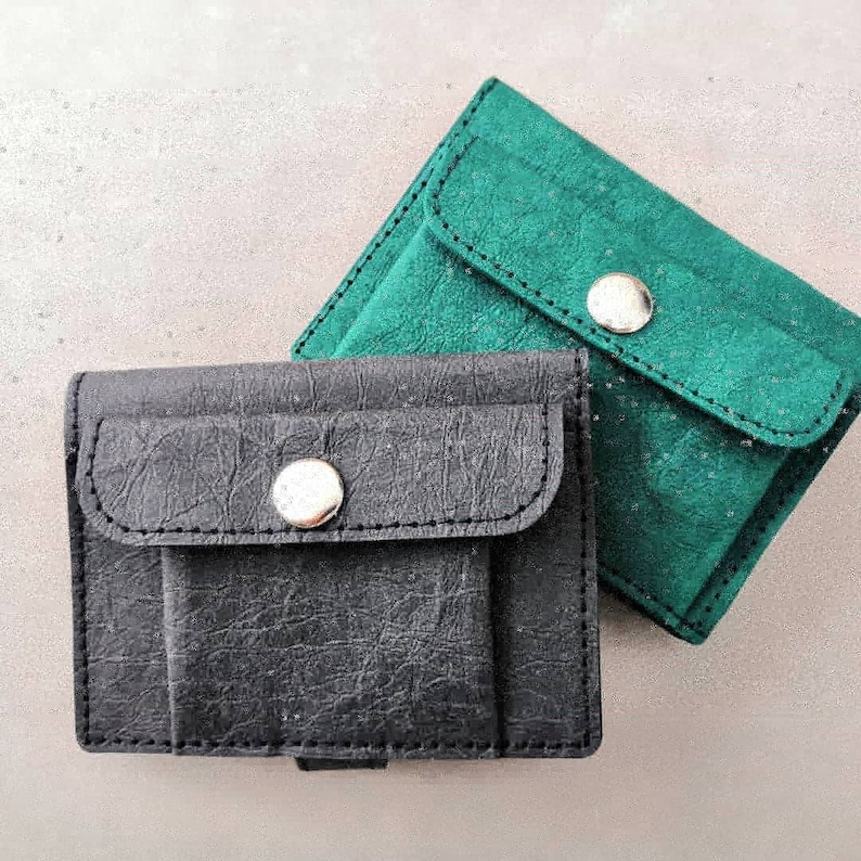 May include: Two leather wallets, one black and one green, with a single snap closure on each.