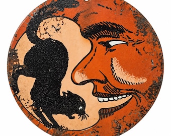 May include: A circular metal sign featuring a distressed orange surface with a black cat silhouette and a large, smiling human face profile. The design includes a small hole at the top for hanging, with visible rust-like texture throughout the orange paint.