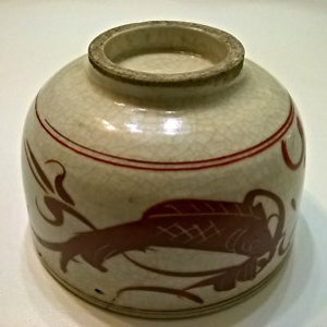 Puede incluir: Un cuenco de cerámica blanca con un borde rojo y un diseño de pez rojo. El cuenco tiene un esmalte craquelado.