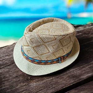May include: A woven fedora hat with a patterned crown and a contrasting brim. The hat features a decorative band with blue, orange, and brown geometric designs. The hat is made of natural fibers and is suitable for sun protection.