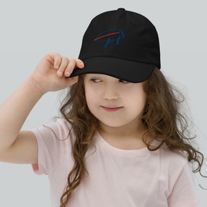 Puede incluir: Una gorra de béisbol negra con un logotipo de búfalo bordado en azul y rojo. La gorra la lleva puesta un niño con el pelo largo y castaño.