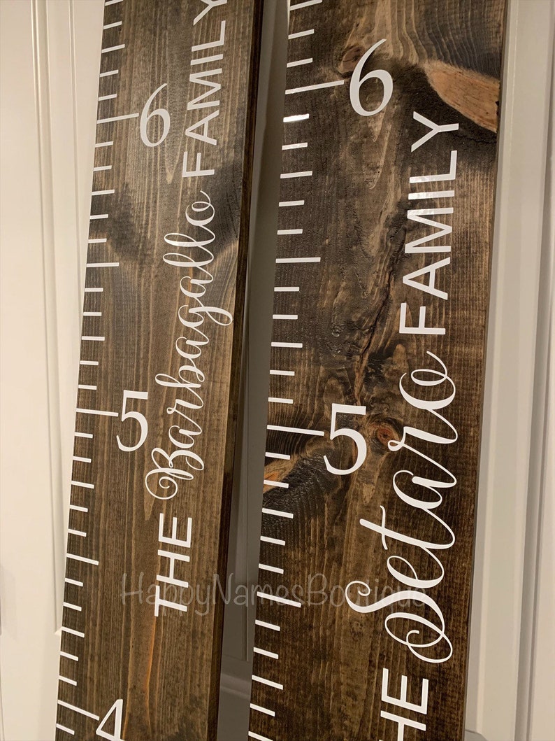 May include: Two wooden growth charts with white numbers and text. The left chart reads "The Barbagallo Family" and the right chart reads "The Dettore Family".