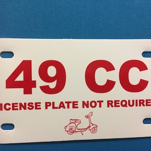 May include: White license plate with red text that reads "49 CC LICENSE PLATE NOT REQUIRED". A small red illustration of a scooter is in the bottom center of the plate.