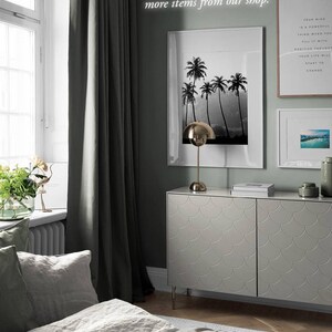 Puede incluir: Un interior de dormitorio con una c&oacute;moda gris con un patr&oacute;n de escamas &uacute;nico, una cama con ropa de cama de lino gris y una ventana con una cortina verde. Hay tres impresiones enmarcadas en la pared, una con una imagen en blanco y negro de palmeras, una con una cita sobre el pensamiento positivo y una con una imagen azul y blanca de agua. El texto en la pared dice "Tu mente es una cosa poderosa cuando la llenas de pensamientos positivos. Tu vida comenzar&aacute; a cambiar."