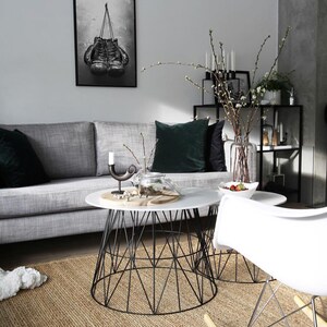 May include: A living room with a gray couch, two black and white coffee tables, a white rocking chair, and a black and white framed print of boxing gloves hanging on the wall.