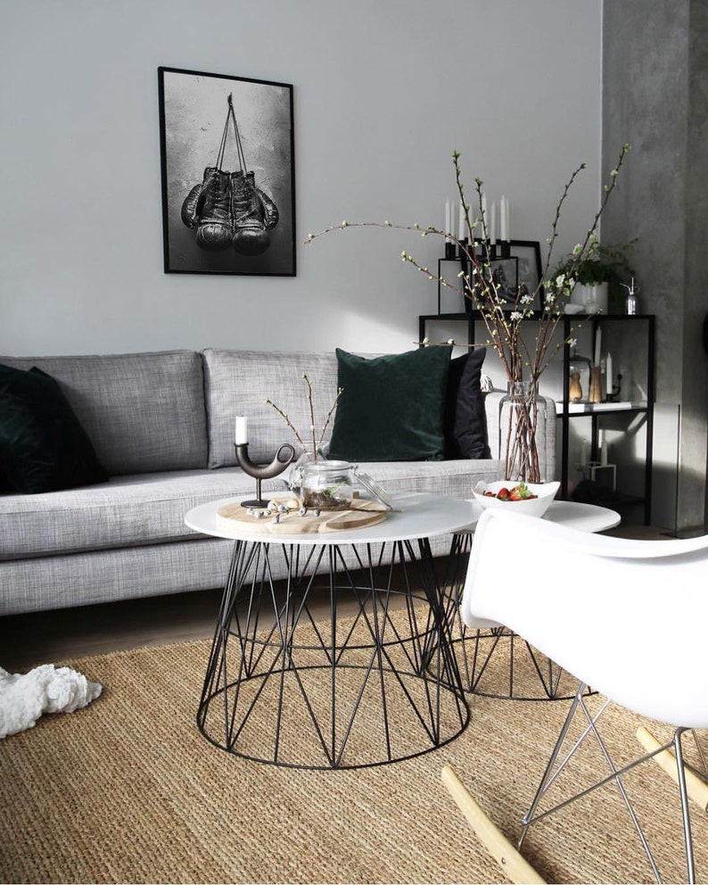 May include: A living room with a gray couch, two black and white coffee tables, a white rocking chair, and a black and white framed print of boxing gloves hanging on the wall.