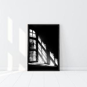 Puede incluir: Fotografía en blanco y negro de una ventana con la luz del sol entrando, proyectando sombras en la pared.