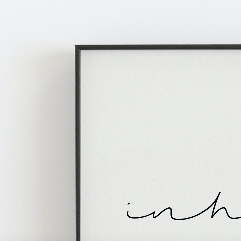 May include: A black framed print with the word "in" written in cursive.