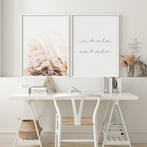 May include: Two framed prints, one with a photograph of dried pampas grass in shades of brown and white, and the other with the text "inhale exhale" in black script.