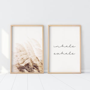 May include: Two framed prints, one with a photograph of tall, feathery grasses in a soft, warm brown tone, and the other with the text "inhale exhale" in black cursive.