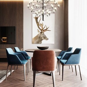 Pode incluir: Uma sala de jantar com uma mesa de madeira e seis cadeiras. A mesa &eacute; redonda e tem um tampo marrom. As cadeiras s&atilde;o estofadas em tecido azul e marrom. Um grande lustre pendura sobre a mesa. Uma impress&atilde;o emoldurada de uma cabe&ccedil;a de veado pendura na parede atr&aacute;s da mesa.