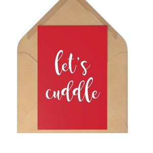 May include: A red greeting card with the words "let's cuddle" in white script is inside a brown envelope. The envelope is sealed and has a triangular flap. The card and envelope are on a white background.