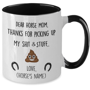 May include: White ceramic coffee mug with a black rim and handle. The mug has a funny saying that reads "Dear Horse Mom, Thanks for picking up my shit & stuff... Love, (Horse's Name)" with a poop emoji and two horseshoes.