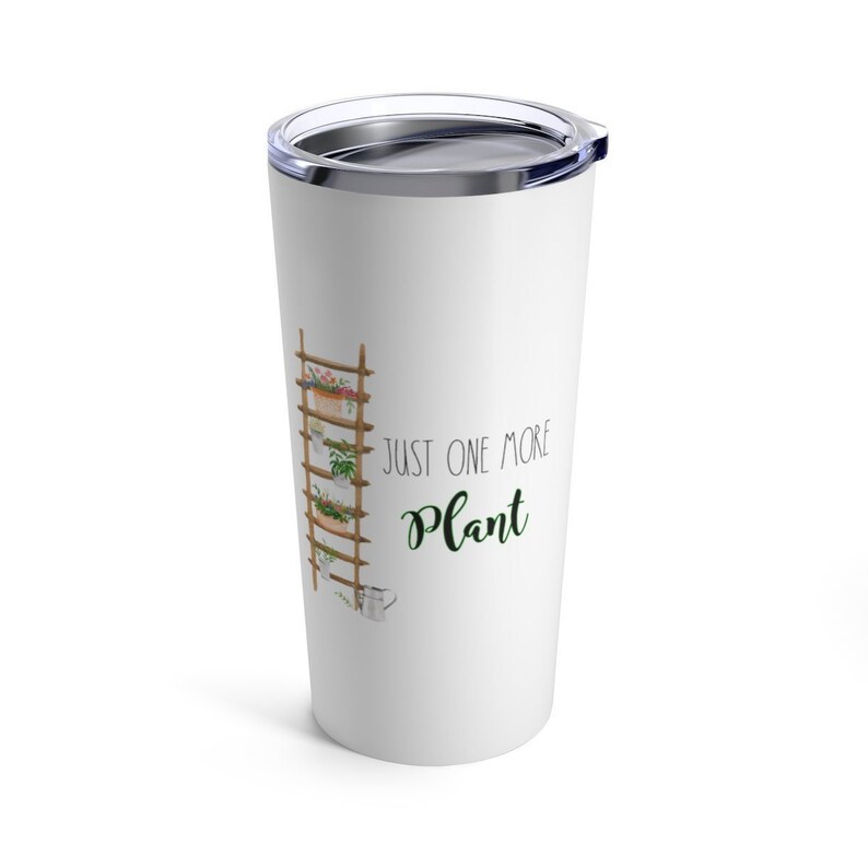 Puede incluir: Vaso blanco con borde y tapa plateados. El vaso presenta una ilustraci&oacute;n en acuarela de una escalera de madera con plantas en macetas y el texto "JUST ONE MORE Plant" en negro y verde.