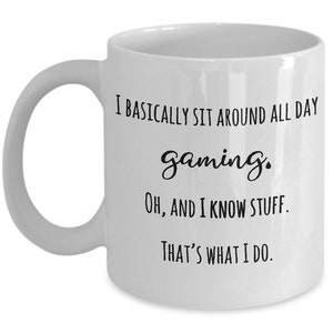 May include: White ceramic mug with a curved handle. The mug features black text that reads: "I BASICALLY SIT AROUND ALL DAY gaming. Oh, AND I KNOW STUFF. THAT'S WHAT I DO."