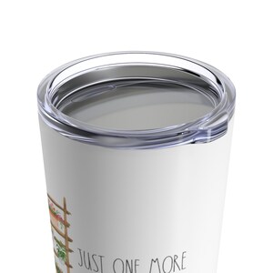 Puede incluir: Vaso de viaje blanco con tapa transparente. El vaso presenta una ilustraci&oacute;n de acuarela de un enrejado de madera con flores y el texto "JUST ONE MORE". El vaso est&aacute; dise&ntilde;ado para mantener las bebidas calientes o fr&iacute;as.