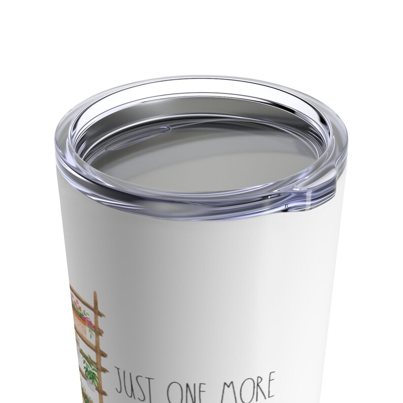 Puede incluir: Vaso de viaje blanco con tapa transparente. El vaso presenta una ilustraci&oacute;n de acuarela de un enrejado de madera con flores y el texto "JUST ONE MORE". El vaso est&aacute; dise&ntilde;ado para mantener las bebidas calientes o fr&iacute;as.