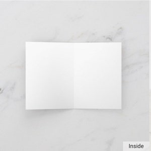 May include: Blank white card folded in half, ready for a handwritten message.