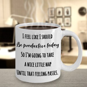 Puede incluir: Taza de caf&eacute; de cer&aacute;mica blanca llena de l&iacute;quido oscuro, con texto negro que dice: "I FEEL LIKE I SHOULD Be productive today SO I'M GOING TO TAKE A NICE LITTLE NAP UNTIL THAT FEELING PASSES."