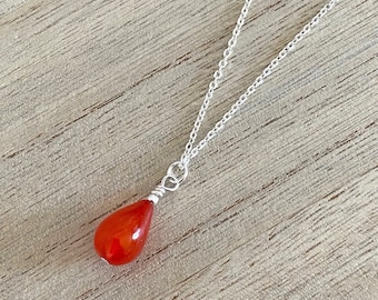 May include: A silver chain necklace with a teardrop-shaped carnelian gemstone pendant.