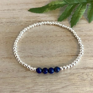 May include: A silver beaded bracelet with four dark blue lapis lazuli beads.