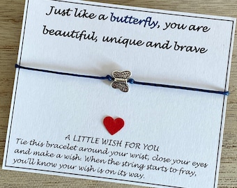 May include: A white card with blue string tied around it. The card has the text "Just like a butterfly, you are beautiful, unique and brave." and "A little wish for you. Tie this bracelet around your wrist, close your eyes and make a wish. When the string starts to fray, you'll know your wish is on its way."
