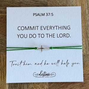 May include: A handmade bracelet with a silver cross charm and green cord is displayed on a white card. The card features the text "PSALM 37:5" and a quote: "COMMIT EVERYTHING YOU DO TO THE LORD. Trust him, and he will help you."