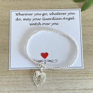 Può includere: Un braccialetto d'argento con un ciondolo a forma di ali d'angelo e un cuore rosso. Il braccialetto viene fornito con un biglietto che recita "Ovunque tu vada, qualunque cosa tu faccia, che il tuo angelo custode vegli su di te."