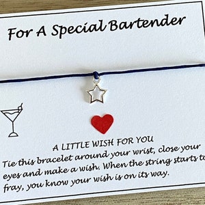 May include: A white card with blue string tied around it. The card says "For A Special Bartender" and "A Little Wish For You". The string has a silver star charm and a red heart charm.