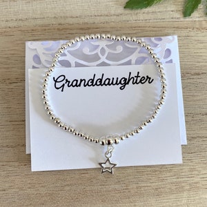 May include: A silver beaded bracelet with a star charm. The bracelet is on a white card with the word "Granddaughter" written on it.