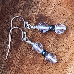 May include: A pair of silver dangle earrings with clear heart-shaped crystal beads and black beads.