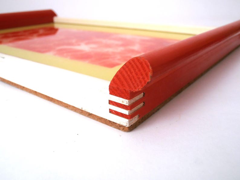 May include: A red and white tray with a rounded edge. The tray is made of wood and has a white interior.
