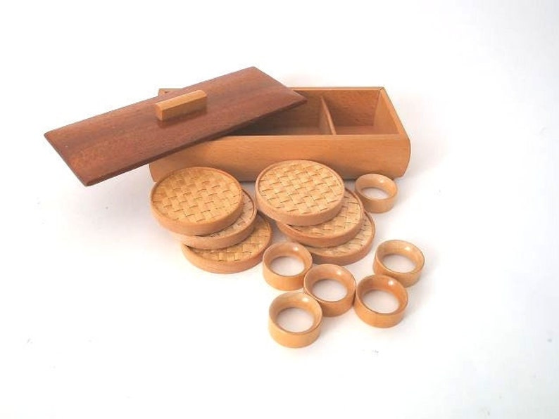May include: A set of wooden coasters with a woven pattern, in a wooden box with a lid. The box has a divided interior.