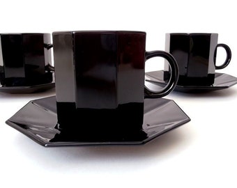 May include: Three black octagonal ceramic teacups and saucers. The cups have a glossy finish and are stacked on top of each other.