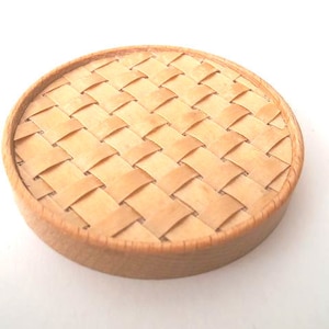 May include: A round, woven, wooden coaster in a light brown colour.