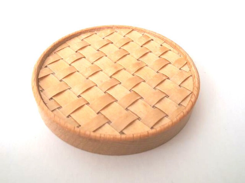 May include: A round, woven, wooden coaster in a light brown colour.