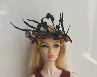 May include: A doll with blonde hair wearing a black and brown headpiece with a beaded design.