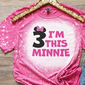 May include: Pink bleached t-shirt with a black number 3 and the text "I'm this Minnie" in pink. The number 3 has a pink bow on top.