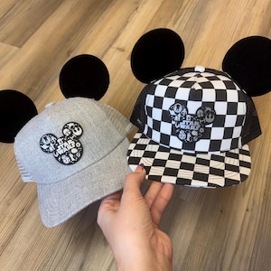 Op de afbeelding: Twee Star Wars baseballpetten met zwarte Mickey Mouse oren. Eén pet is grijs met een Star Wars logo, de andere is zwart-wit geblokt. Beide petten hebben een mesh rug.