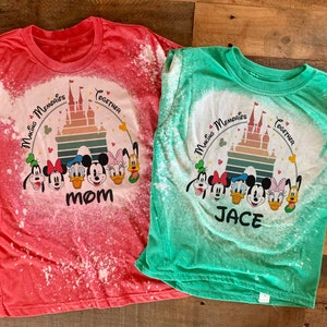 May include: Two bleached t-shirts with a Disney theme. One shirt is red with the text "Mom" and the other is green with the text "Jace". Both shirts feature a graphic of Mickey Mouse and friends in front of Cinderella's Castle with the text "Magic Memories Together".