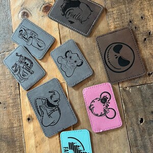 May include: A collection of eight leather patches with various designs, including a car, a lion, a skull, a character from The Nightmare Before Christmas, Mickey Mouse, a castle, and the word "Faith".