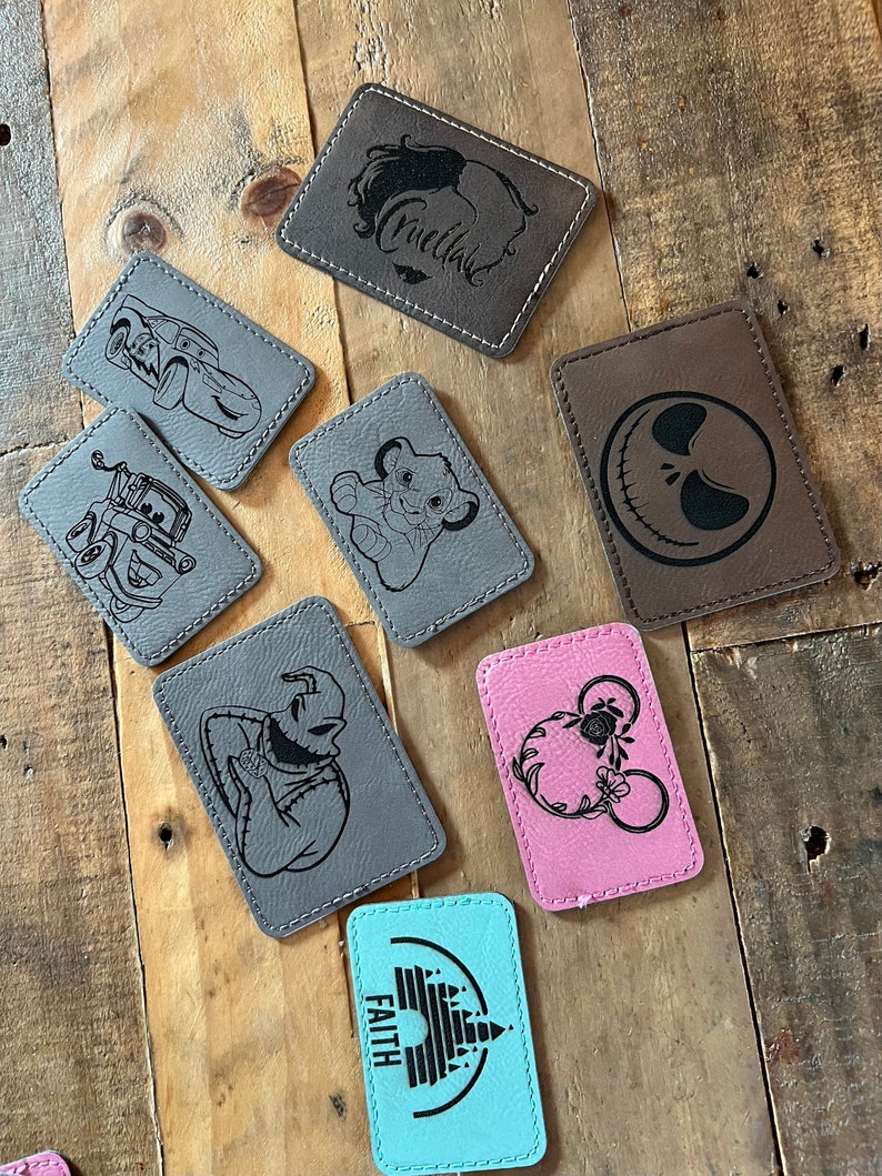 May include: A collection of eight leather patches with various designs, including a car, a lion, a skull, a character from The Nightmare Before Christmas, Mickey Mouse, a castle, and the word "Faith".