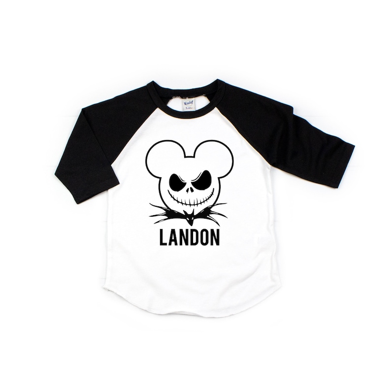 Puede incluir: Camiseta de b&eacute;isbol blanca y negra con una cabeza de Mickey Mouse en blanco y negro con una cara de Jack Skellington y el nombre Landon impreso debajo.