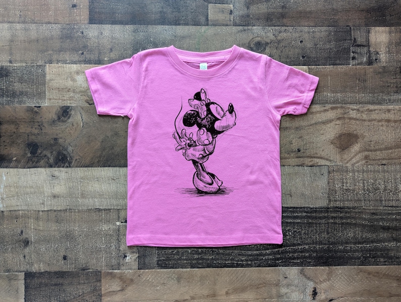 May include: Pink t-shirt with a black and white illustration of a cartoon mouse with a bow.