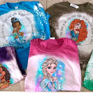 Peut inclure: Une collection de huit t-shirts blanchis et tie-dye repr&eacute;sentant des princesses Disney. Chaque t-shirt pr&eacute;sente une princesse diff&eacute;rente et une citation du film. Les t-shirts sont de diff&eacute;rentes couleurs, notamment bleu, vert, rose, violet et rouge.