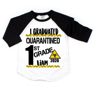 May include: A white and black baseball style t-shirt with the text "I Graduated Quarantined 1st Grade Liam 2020" and a yellow caution tape design.
